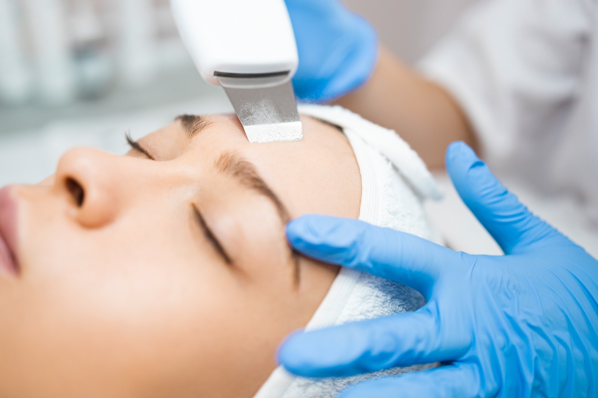 Close-up of woman receiving ultrasound facial peeling. Skin care procedure.