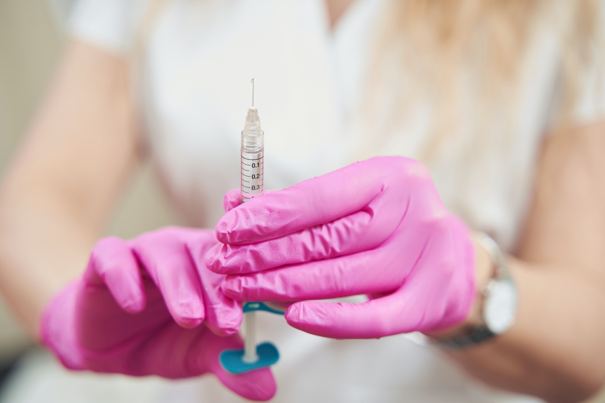 Unrecognized doctor in pink gloves with syringe in hand