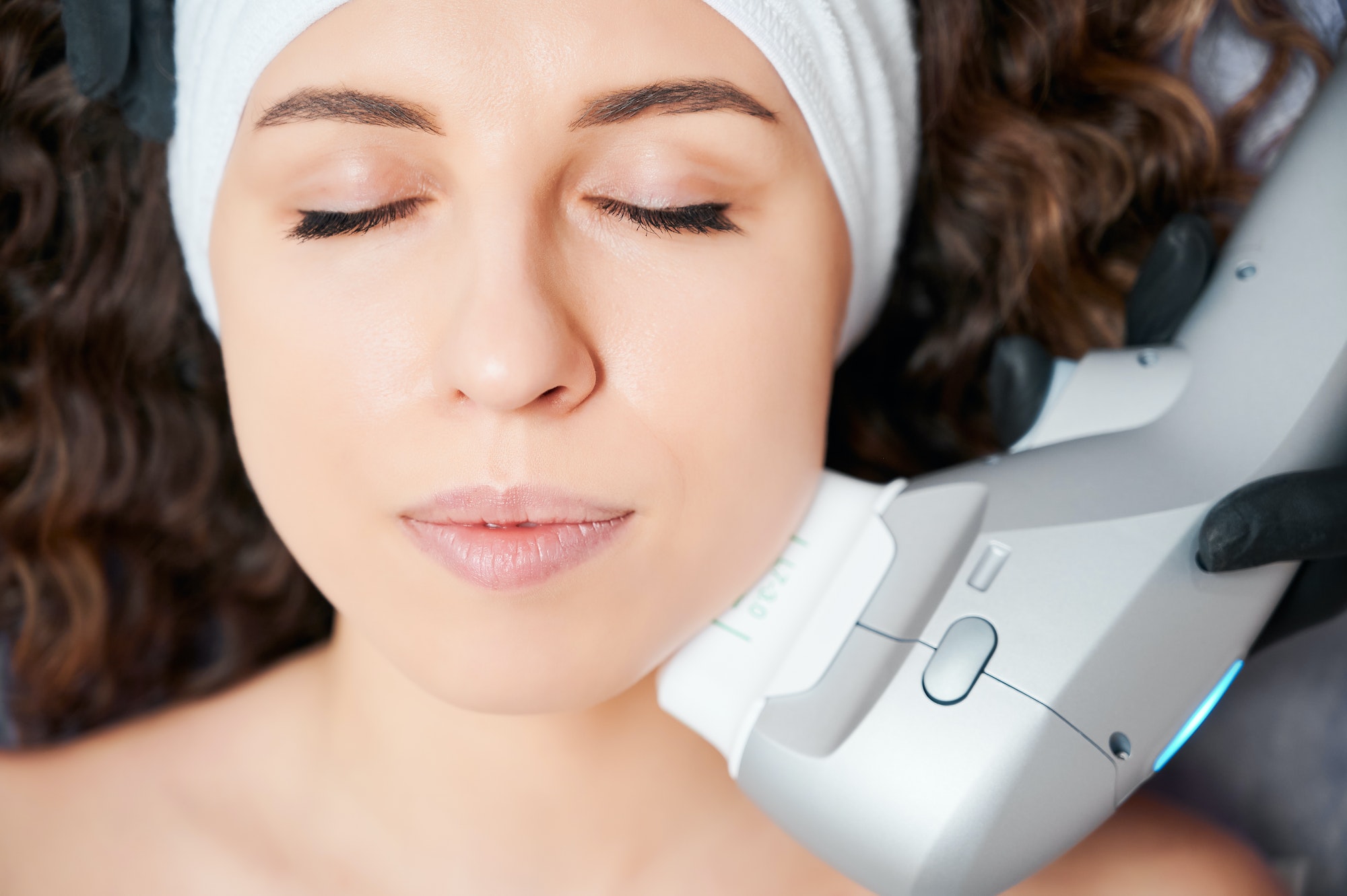 Young cute woman doing skin care procedure with equipment.